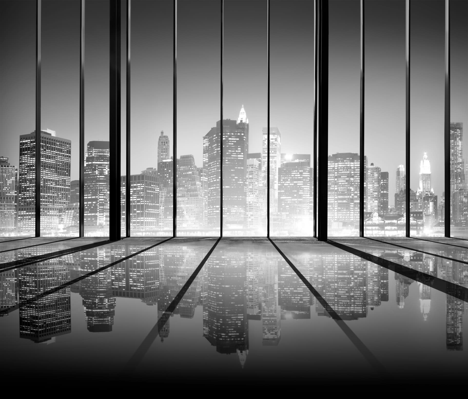 Escritório vazio com janelas do chão ao teto refletindo o skyline noturno